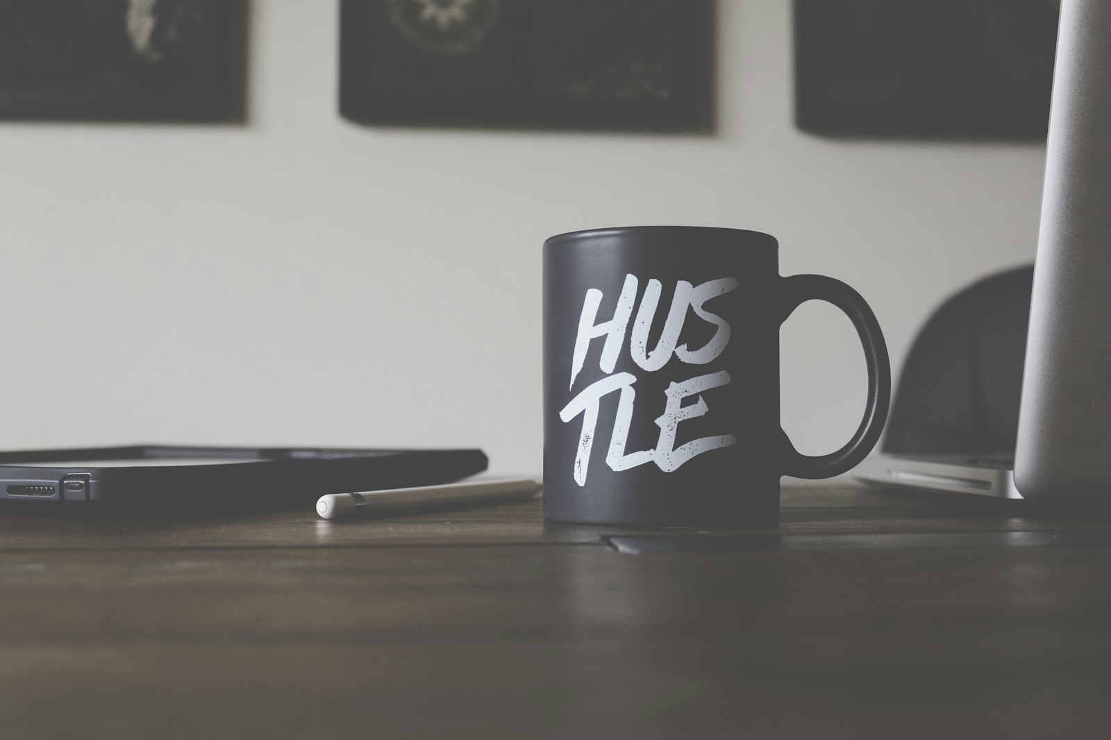 Meja kerja dengan cangkir bertuliskan hustle menggambarkan semangat mencari cara mendapatkan income tambahan