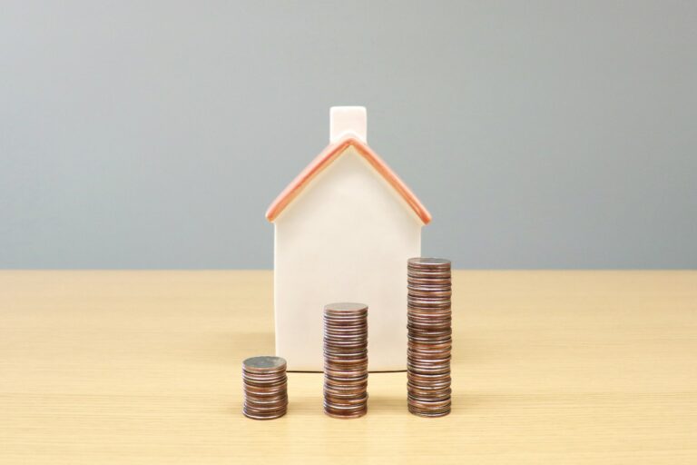 Miniatur rumah dan tumpukan koin menggambarkan berbagai jenis passive income seperti properti sewa dan dividen