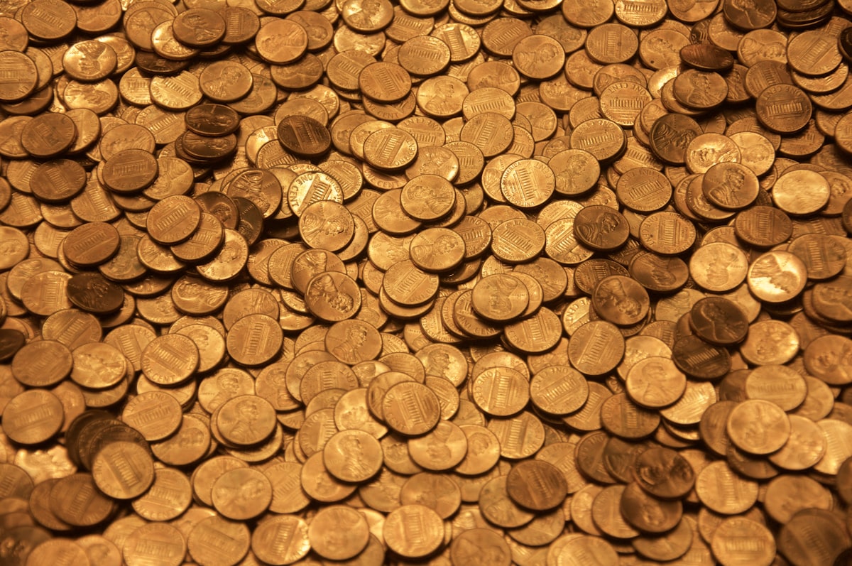 Koin coklat di atas permukaan kayu - mengubah uang menjadi aset emas