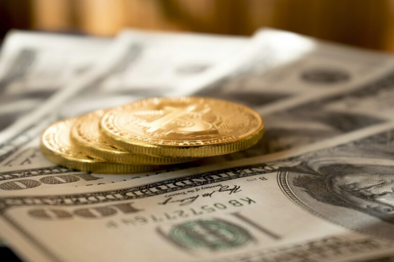 Koin emas di atas uang kertas dolar, ilustrasi aturan pajak emas dalam investasi